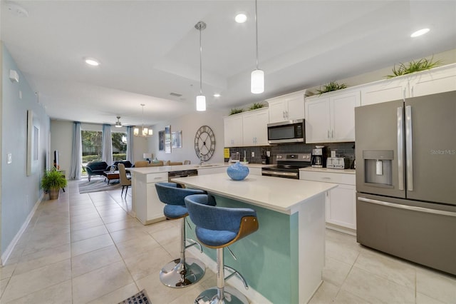 kitchen with appliances with stainless steel finishes, hanging light fixtures, kitchen peninsula, and white cabinets