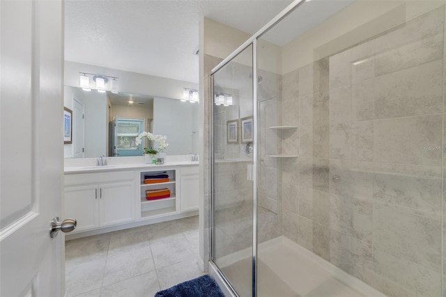 bathroom featuring tile patterned floors, a shower with shower door, and vanity