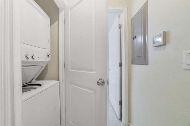 clothes washing area featuring stacked washer and clothes dryer, electric panel, and light tile patterned floors