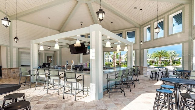 kitchen with high vaulted ceiling, beamed ceiling, a breakfast bar, and pendant lighting