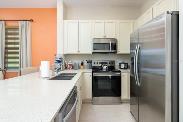 kitchen with light stone countertops, stainless steel appliances, white cabinets, and sink