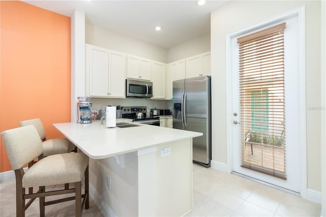 kitchen with white cabinets, sink, kitchen peninsula, appliances with stainless steel finishes, and a kitchen breakfast bar