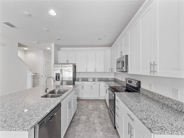 kitchen featuring white cabinets, a center island with sink, appliances with stainless steel finishes, and sink