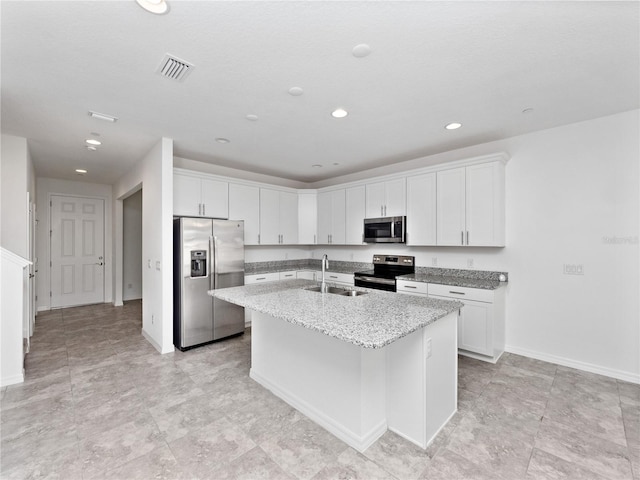 kitchen with appliances with stainless steel finishes, light stone counters, an island with sink, white cabinets, and sink