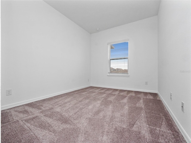 empty room featuring lofted ceiling and carpet