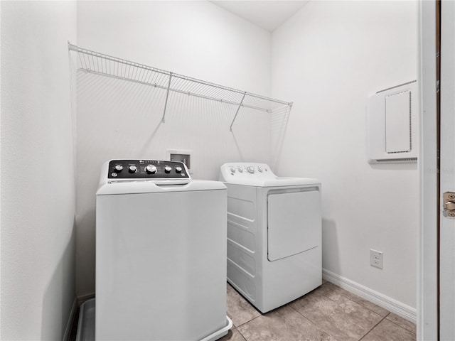 laundry area with independent washer and dryer and light tile patterned floors