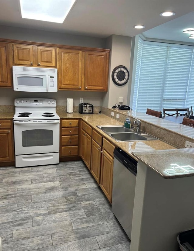 kitchen featuring kitchen peninsula, sink, and white appliances