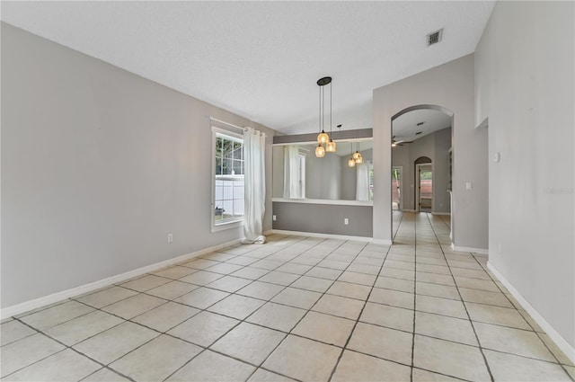 tiled spare room with vaulted ceiling, a textured ceiling, and a chandelier