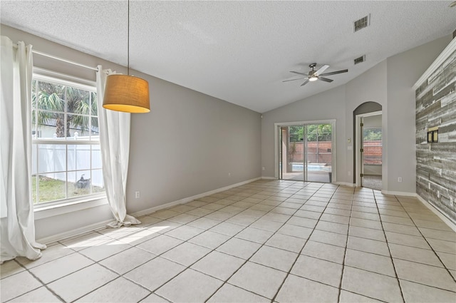 unfurnished room with vaulted ceiling, ceiling fan, light tile patterned floors, and a textured ceiling