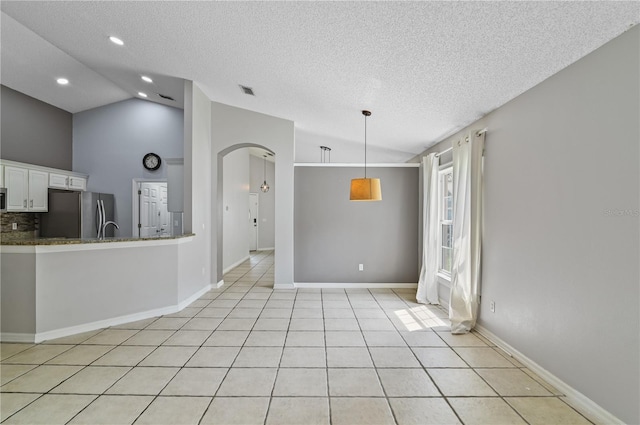 unfurnished room with vaulted ceiling, a textured ceiling, and light tile patterned floors