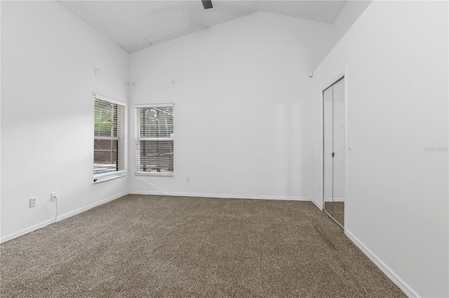 carpeted spare room featuring high vaulted ceiling