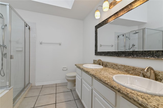 bathroom featuring tile patterned flooring, a skylight, a shower with door, vanity, and toilet