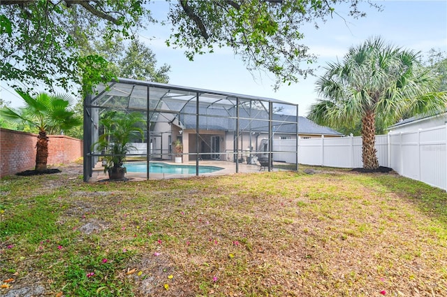 back of property with a lanai, a patio, a fenced in pool, and a lawn