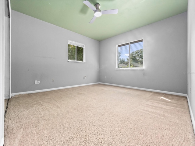 carpeted spare room with a wealth of natural light and ceiling fan