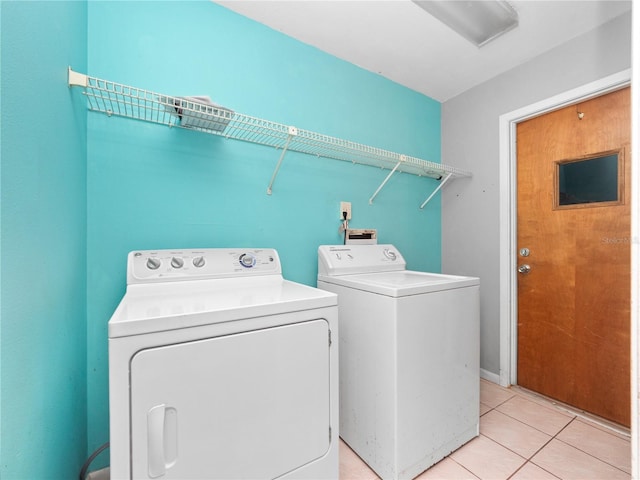 laundry area with independent washer and dryer and light tile patterned floors