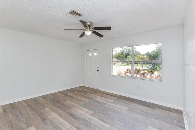 foyer entrance with ceiling fan, a textured ceiling, and light hardwood / wood-style floors