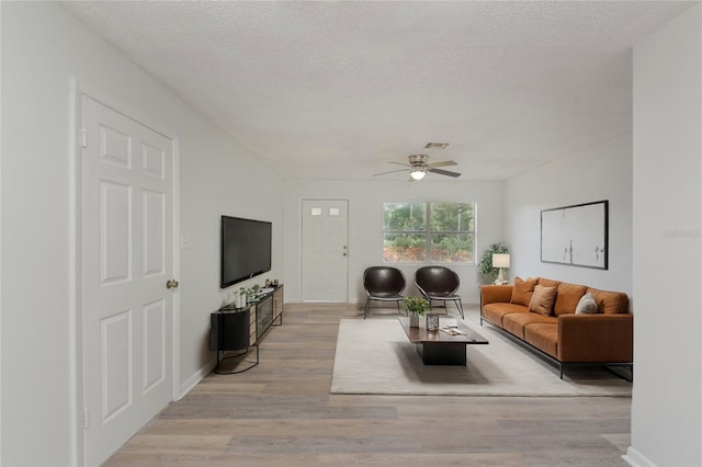 living room featuring a textured ceiling, ceiling fan, and light hardwood / wood-style flooring