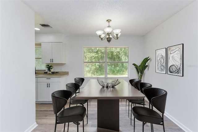 office space with a textured ceiling, light hardwood / wood-style floors, and a notable chandelier