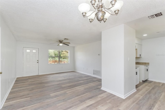 interior space featuring ceiling fan with notable chandelier, a textured ceiling, and light hardwood / wood-style flooring