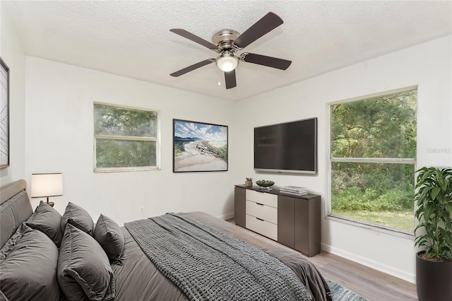 bedroom with light wood-type flooring, a textured ceiling, and ceiling fan