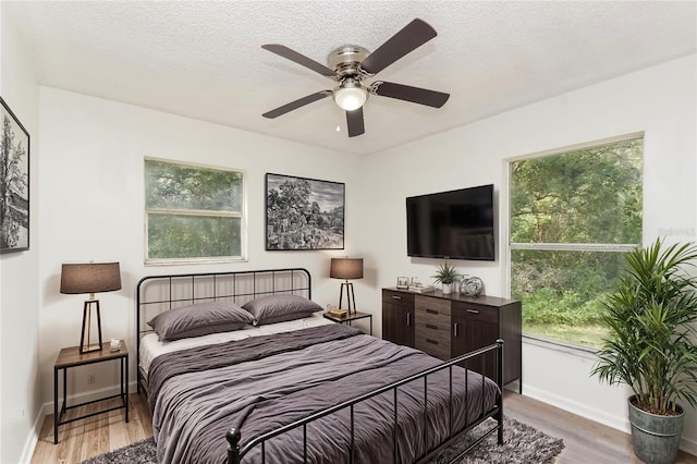 bedroom with ceiling fan, a textured ceiling, and light hardwood / wood-style flooring