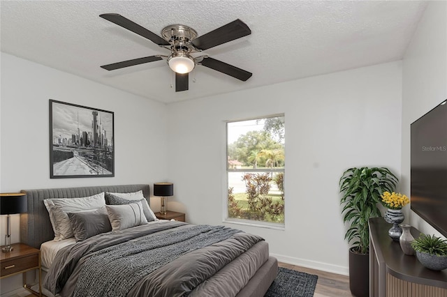 bedroom with ceiling fan, a textured ceiling, and wood-type flooring