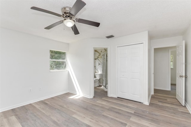 unfurnished bedroom with ceiling fan, connected bathroom, a textured ceiling, a closet, and light hardwood / wood-style floors