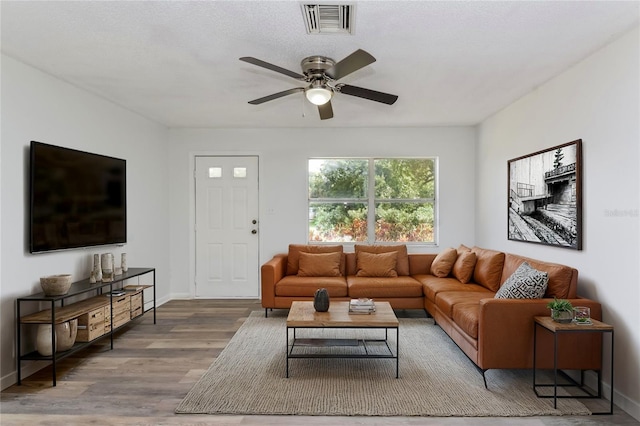 living room with ceiling fan, hardwood / wood-style floors, and a textured ceiling