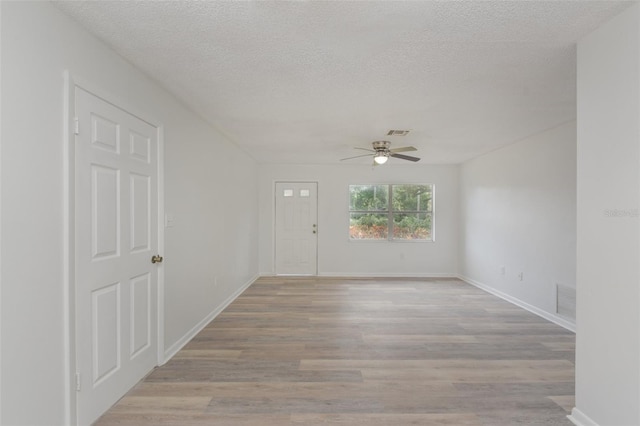 unfurnished room with ceiling fan, a textured ceiling, and light hardwood / wood-style flooring