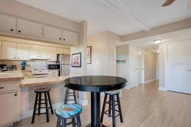 kitchen featuring stainless steel fridge, electric stove, a breakfast bar, light wood-type flooring, and ceiling fan