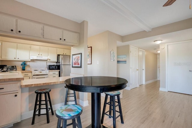 3150 N Atlantic Ave Unit 3-550, Cocoa Beach, FL 32931 - kitchen featuring freestanding refrigerator, under cabinet range hood, light wood-type flooring, a peninsula, and a breakfast bar area