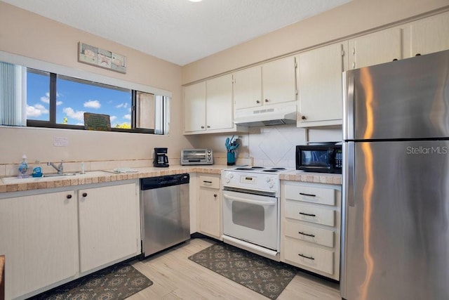 3150 N Atlantic Ave Unit 3-550, Cocoa Beach, FL 32931 - kitchen with stainless steel appliances, under cabinet range hood, light countertops, a sink, and light wood-type flooring