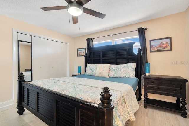 bedroom featuring a textured ceiling, light hardwood / wood-style flooring, ceiling fan, and a closet