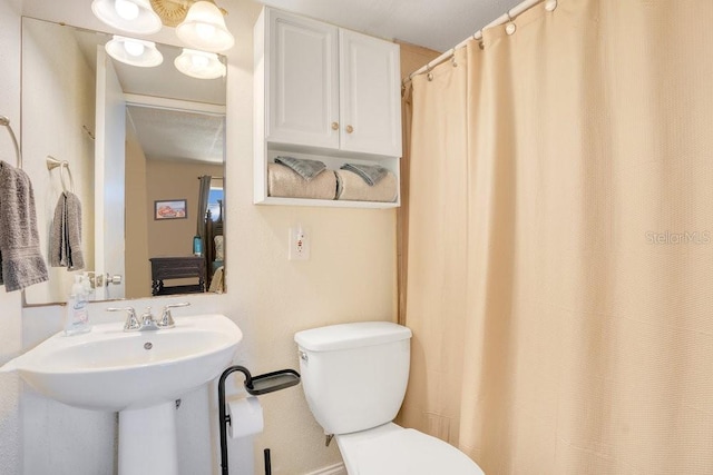 bathroom featuring toilet, a shower with shower curtain, and sink