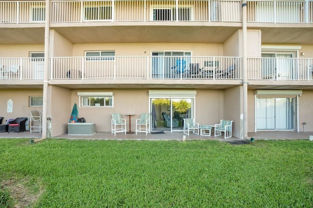 3150 N Atlantic Ave Unit 3-550, Cocoa Beach, FL 32931 - rear view of property featuring stucco siding, a patio area, and a yard