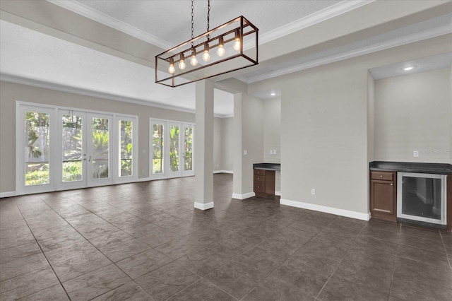 unfurnished living room featuring dark tile patterned flooring, crown molding, beverage cooler, and french doors