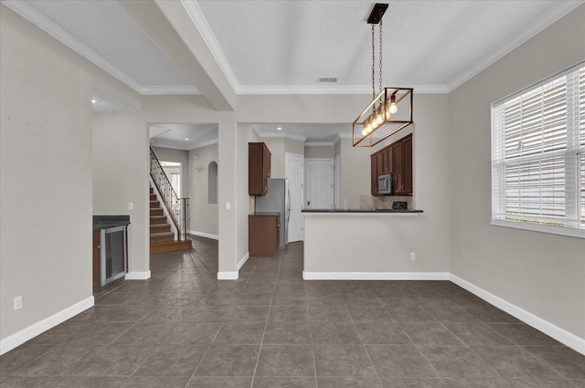 unfurnished living room featuring a textured ceiling, ornamental molding, and dark tile patterned floors