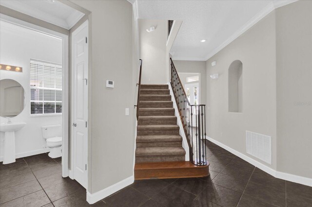 stairway featuring ornamental molding and tile patterned floors