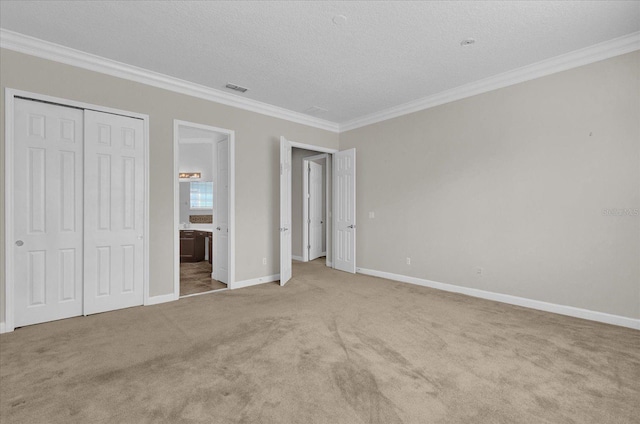 unfurnished bedroom featuring a textured ceiling, crown molding, light colored carpet, and a closet