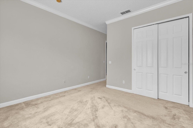 unfurnished bedroom featuring a textured ceiling, crown molding, light carpet, and a closet