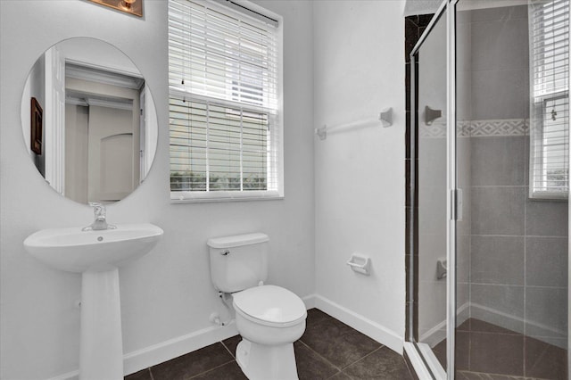 bathroom featuring a wealth of natural light, tile patterned floors, an enclosed shower, and toilet