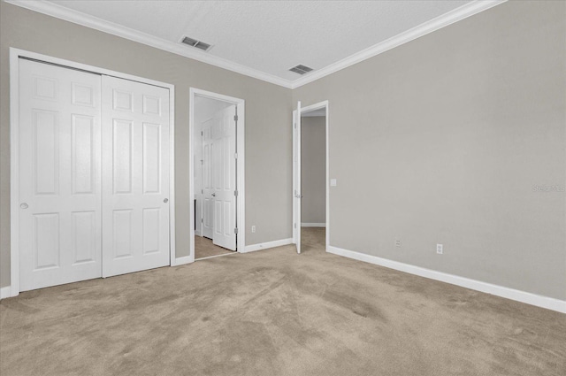 unfurnished bedroom with a textured ceiling, ornamental molding, light colored carpet, and a closet