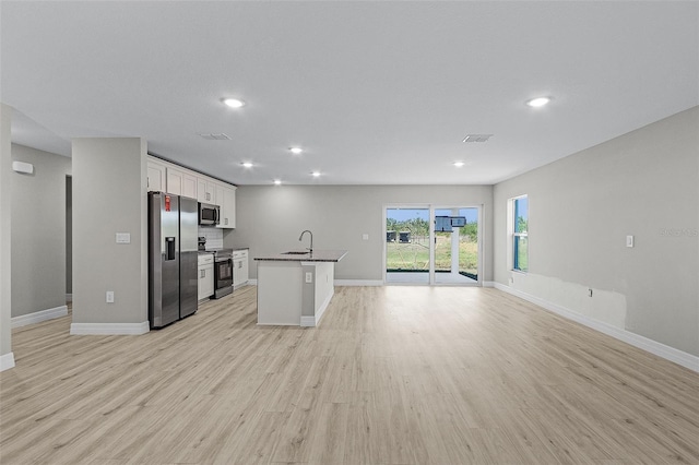 kitchen with appliances with stainless steel finishes, sink, a center island with sink, white cabinets, and light hardwood / wood-style floors