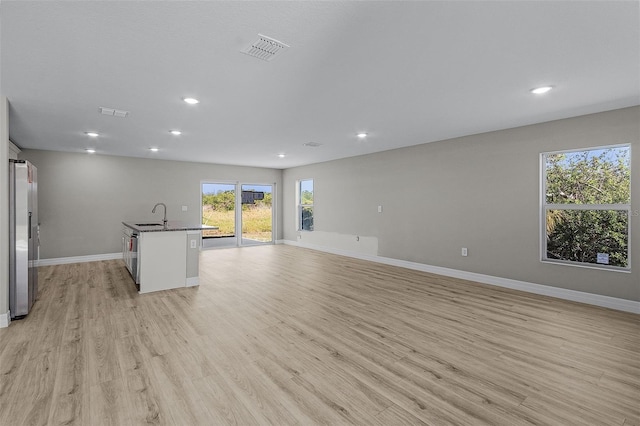 unfurnished living room featuring light wood-type flooring and sink