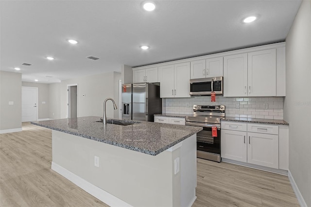 kitchen with sink, white cabinetry, stainless steel appliances, and a kitchen island with sink