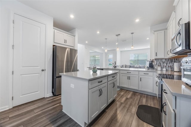 kitchen with a center island, stainless steel appliances, hanging light fixtures, and dark hardwood / wood-style floors