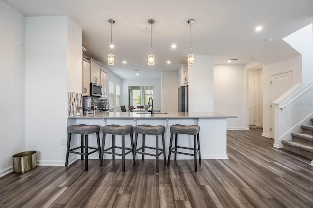 kitchen with kitchen peninsula, white cabinets, decorative light fixtures, and appliances with stainless steel finishes