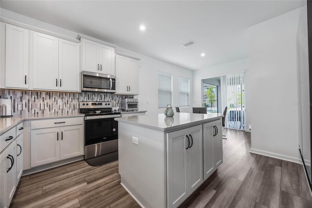 kitchen with white cabinetry, a center island, dark hardwood / wood-style flooring, decorative backsplash, and appliances with stainless steel finishes