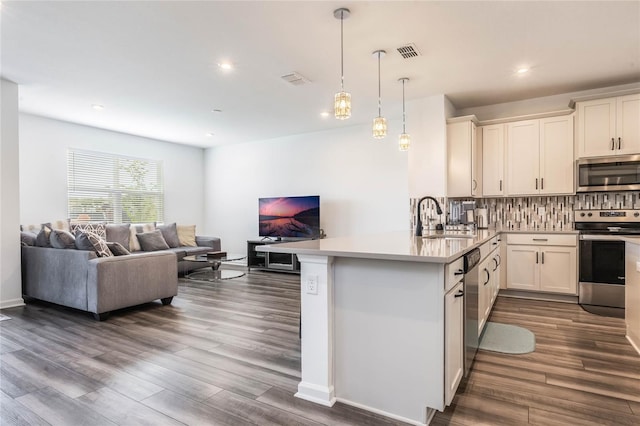 kitchen featuring sink, stainless steel appliances, tasteful backsplash, kitchen peninsula, and pendant lighting