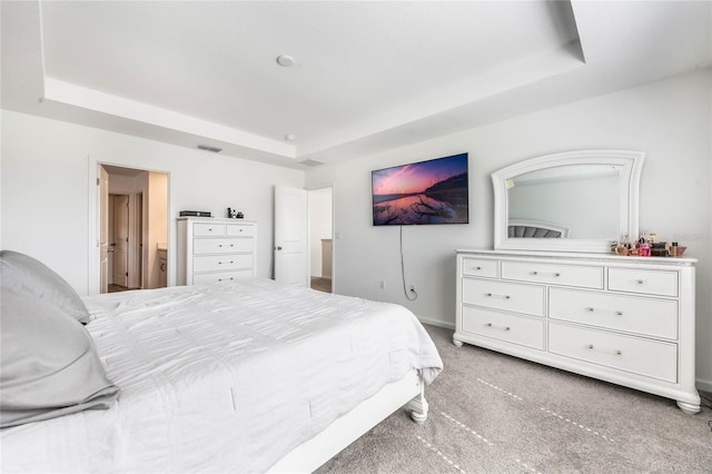 bedroom featuring light carpet, connected bathroom, and a tray ceiling